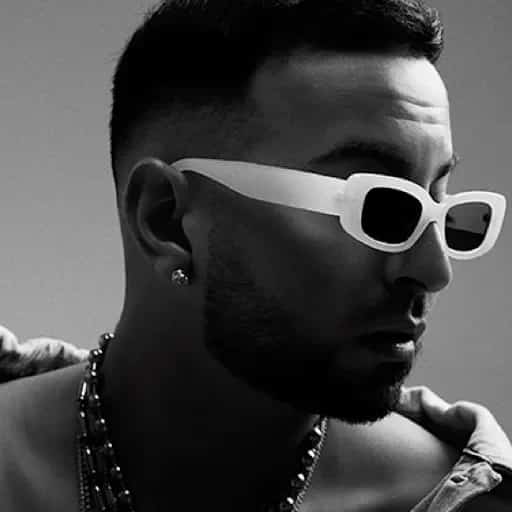 Primer plano en blanco y negro de Justin Quiles con gafas de sol blancas y el rostro girado hacia la derecha.