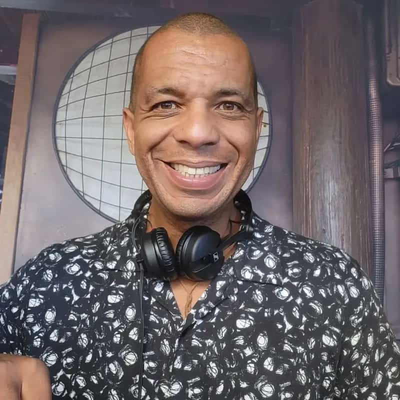 DJ Paulinho sonriendo a cámara con auriculares alrededor del cuello, imagen de perfil para sus sesiones de música comercial y afrohouse