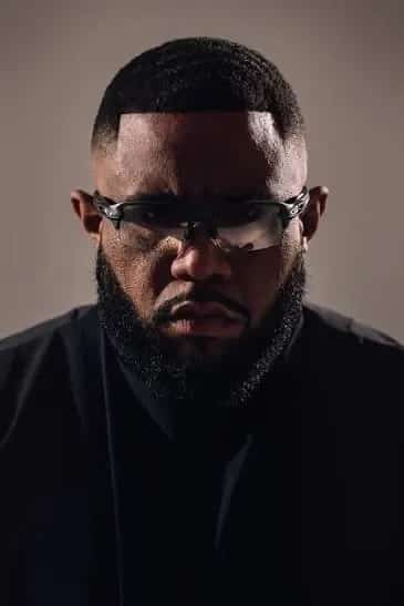 Retrato de GIMS con gafas de sol negras y jersey blanco de cuello alto, imagen de perfil del cantante y rapero francófono.