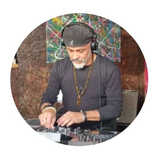 DJ Pakko 2K smiling with headphones in hand on a Marbella seafront, veteran vinyl selector and event DJ.