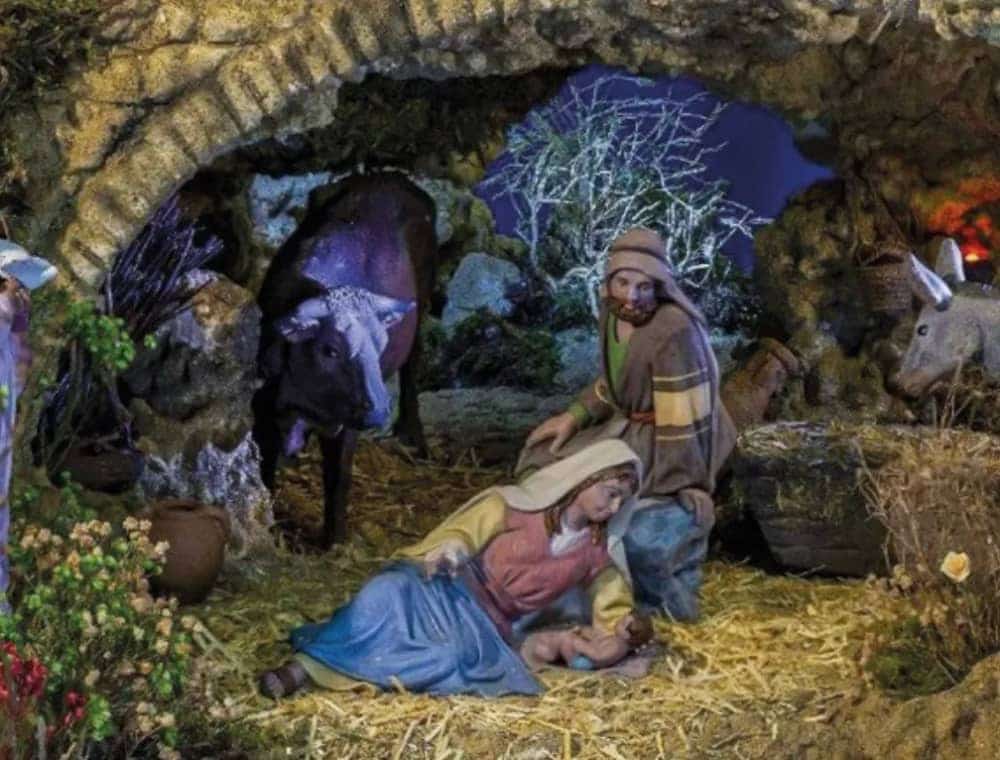 Close-up of a traditional Nativity scene from the Marbella Nativity Route 2025 showing Mary, Joseph and Baby Jesus in a stone stable with an ox and a donkey in the background.