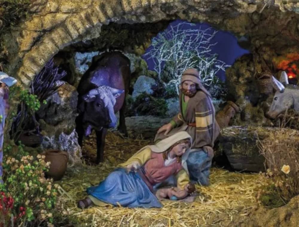 Close-up of a traditional Nativity scene from the Marbella Nativity Route 2025 showing Mary, Joseph and Baby Jesus in a stone stable with an ox and a donkey in the background.