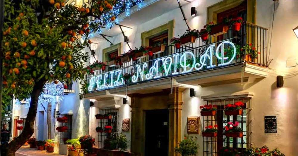 Luces de Navidad Marbella 2025 en el Ayuntamiento de Marbella, con el letrero “Feliz Navidad” iluminando la fachada en la Plaza de los Naranjos y los naranjos decorados por las fiestas.