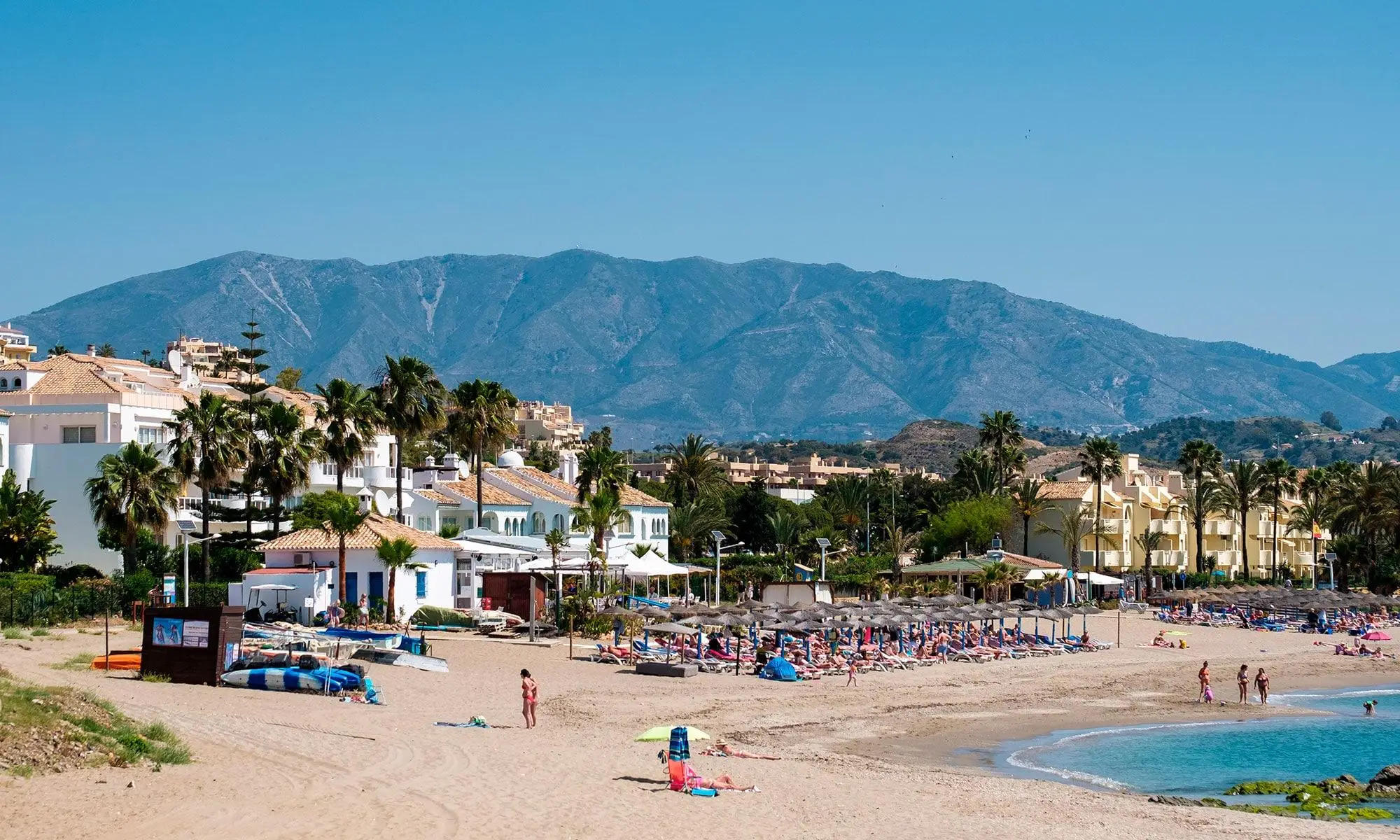 Playa de La Cala de Mijas con arena dorada, palmeras y montañas de fondo en Costa del Sol
