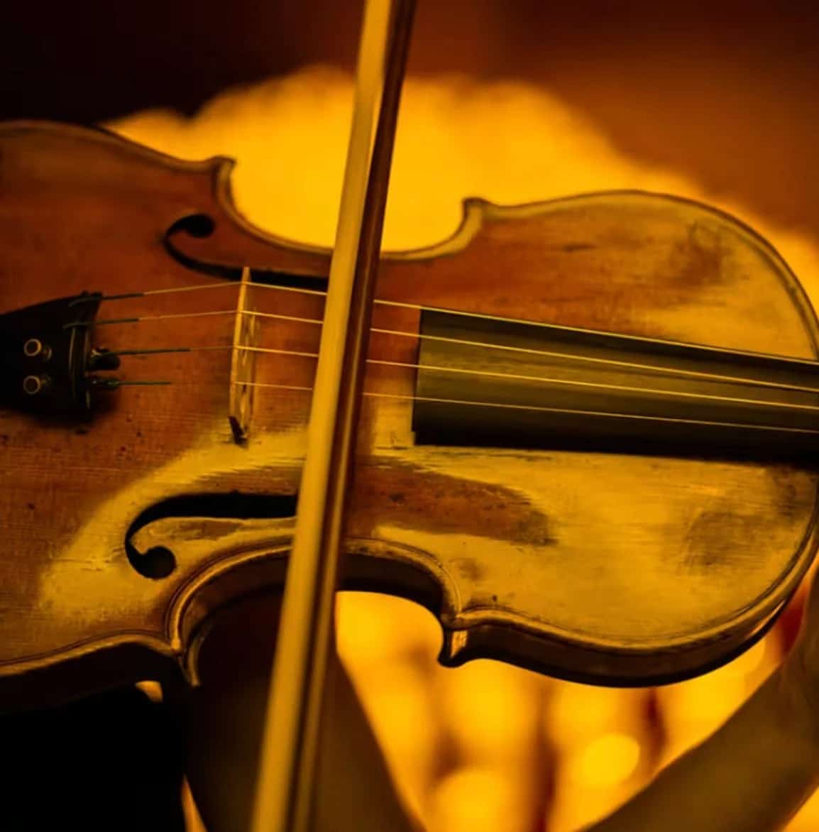 Promotional poster for “Candlelight: Tribute to Queen” showing a stage filled with hundreds of glowing candles, the silhouette of a string quartet performing live and the concert title prominently displayed on an elegant dark background.