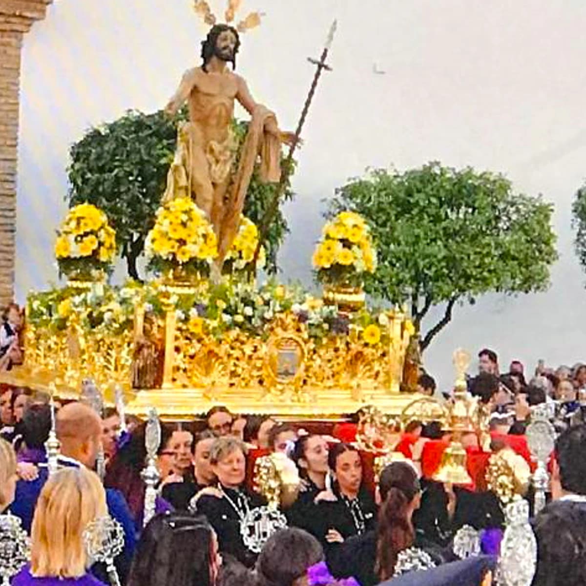 Procesión del Resucitado en Marbella durante el Domingo de Resurrección, con el trono dorado de Cristo Resucitado rodeado de público, músicos y cortejo en la Plaza de la Iglesia.
