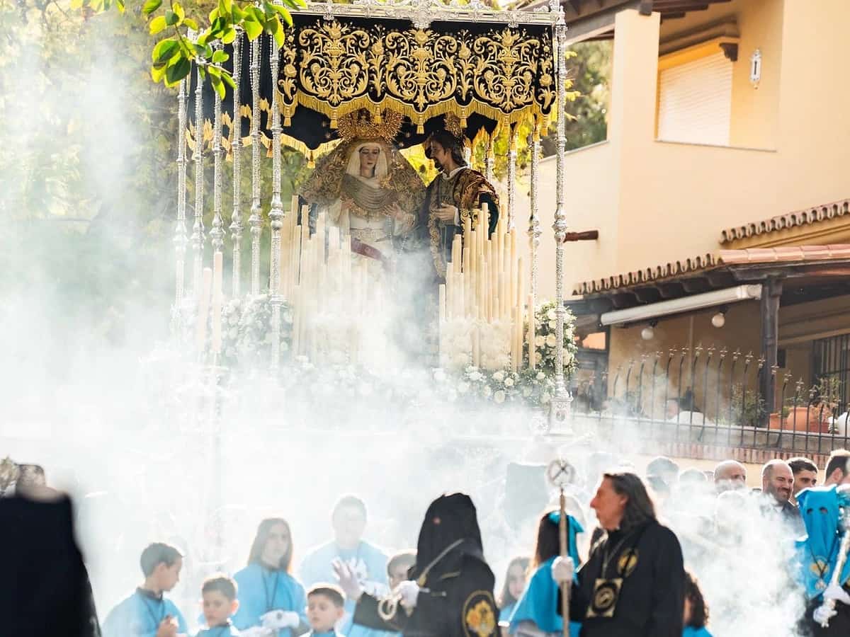 Procesión del Calvario en Marbella durante el Jueves Santo, con el trono de María Santísima del Calvario y San Juan Evangelista entre incienso, cirios y cortejo cofrade a su paso por la ciudad.