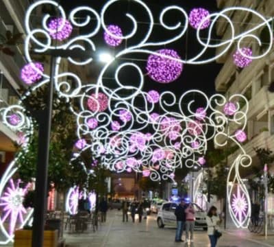 Luces de Navidad con esferas moradas decorando una calle peatonal en Navidad Marbella, con gente paseando de noche