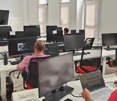 Desarrolladores trabajando en StartUps Festival Marbella 2025, puestos con monitores y portátiles en MarbellUp durante el hackathon turístico