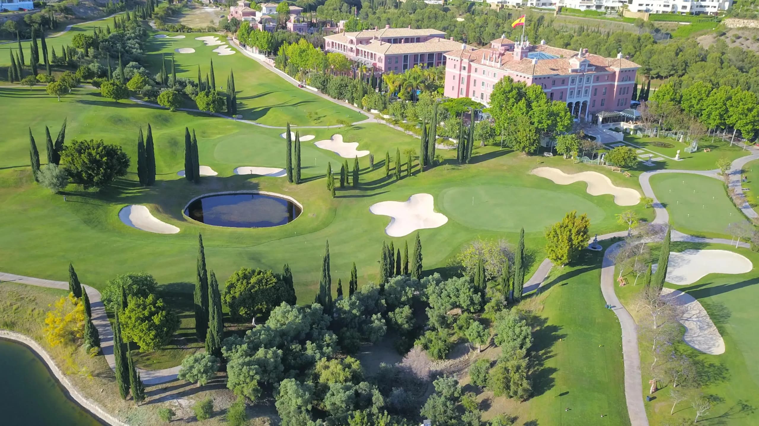 Aerial view of Villa Padierna Golf Course in Marbella, Costa del Sol, featuring manicured greens, sand bunkers, cypress trees, and the Villa Padierna Palace Hotel in the background.