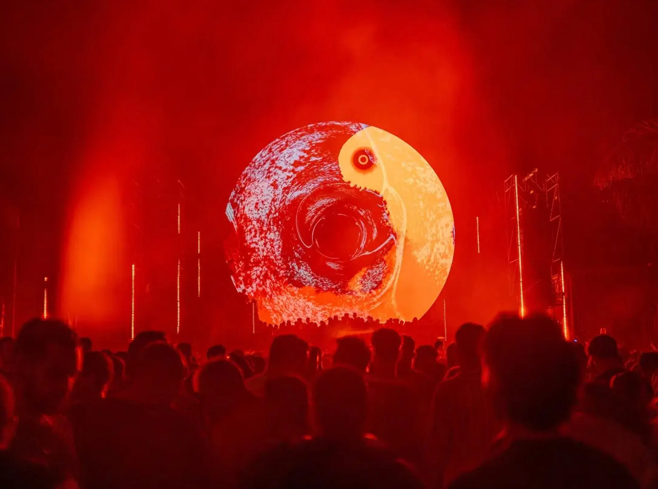 Live concert in Málaga featuring an immersive visual show with red lighting, digital projections, and a large audience.
