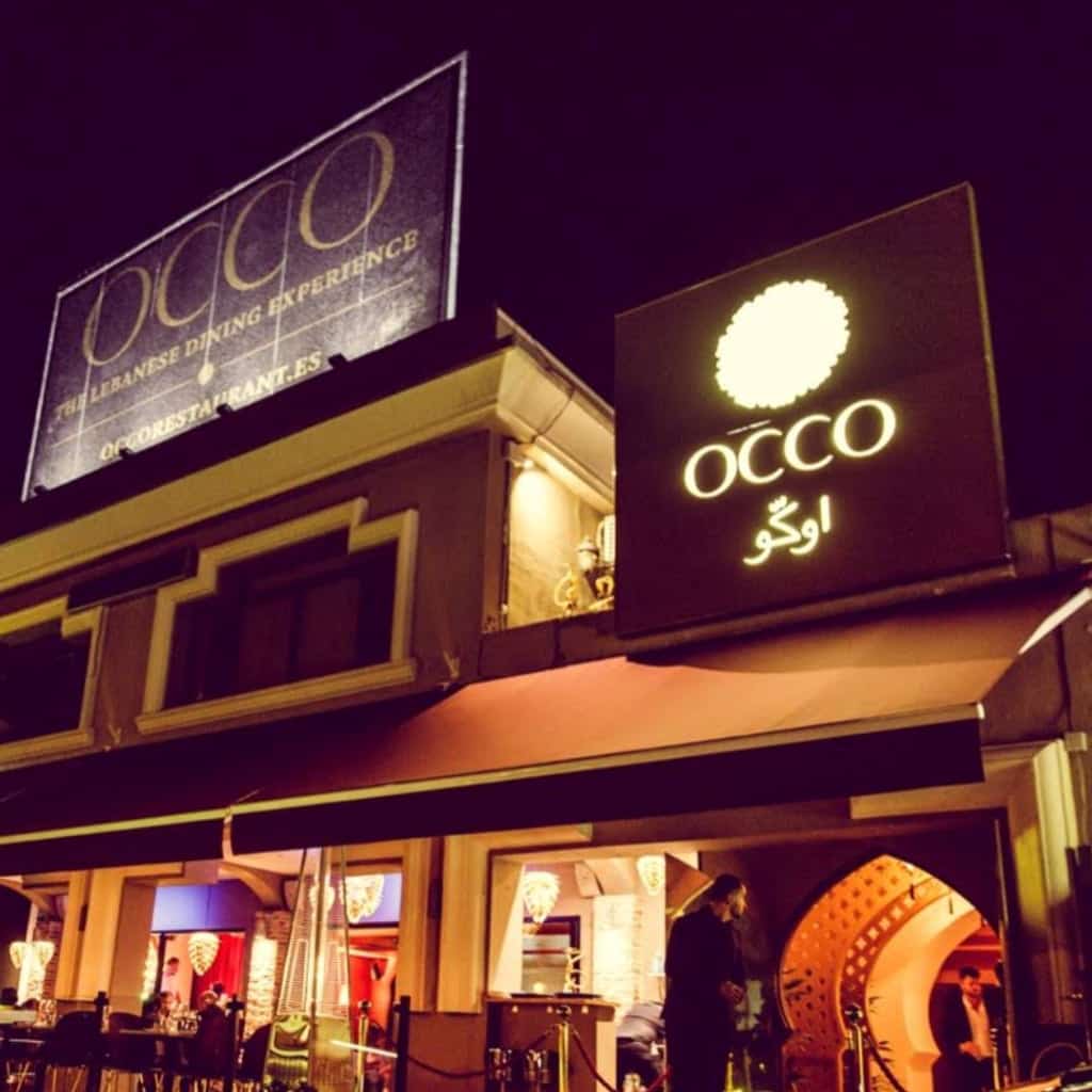 Fachada nocturna de OCCO Marbella con rótulo iluminado, punto de referencia para cena y fiesta libanesa junto a Puerto Banús.