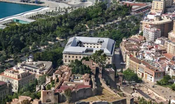 Palmeras imponentes en la Plaza de la Aduana con el Museo de Málaga al fondo.