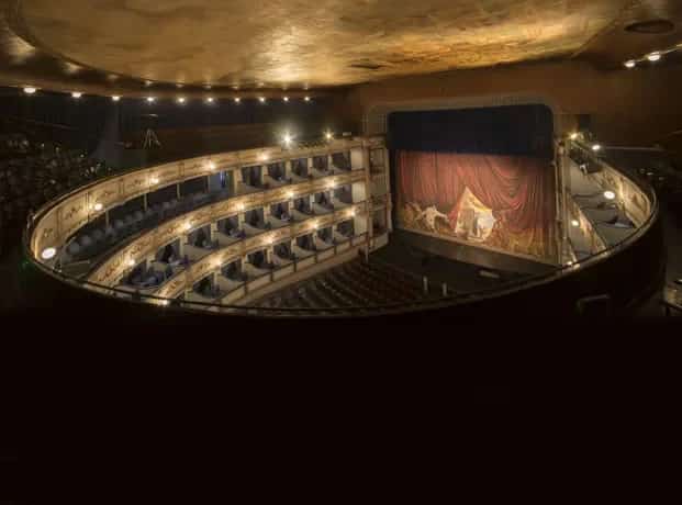 Vista interior del Teatro Cervantes en Málaga, mostrando el elaborado mural del techo del siglo XIX con su alegoría de la economía de la ciudad y las Bellas Artes.